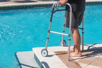 Personne à mobilité réduite en bord de piscine avec son déambulateur